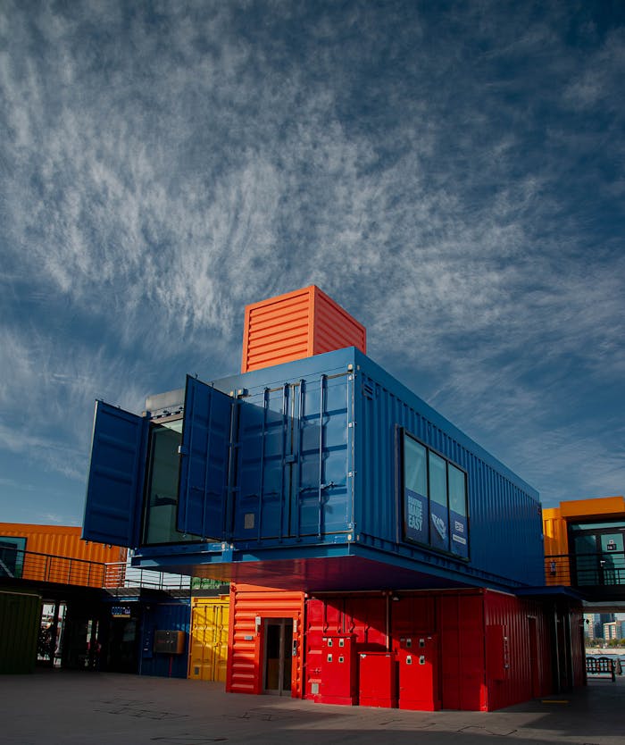 Vibrant shipping containers arranged creatively under a bright sky, showcasing modern architectural innovation.